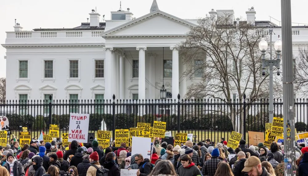 Protesters gathered outside the White House with placards. One says "Trump is a war criminal", others say "Stop bombing Venezuela now"
